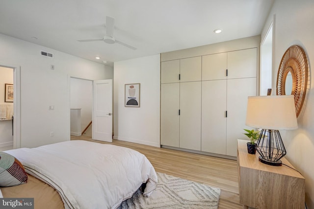 bedroom with a closet, light hardwood / wood-style floors, and ceiling fan