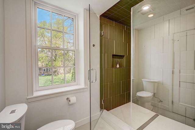 bathroom with a wealth of natural light, a shower with shower door, and toilet