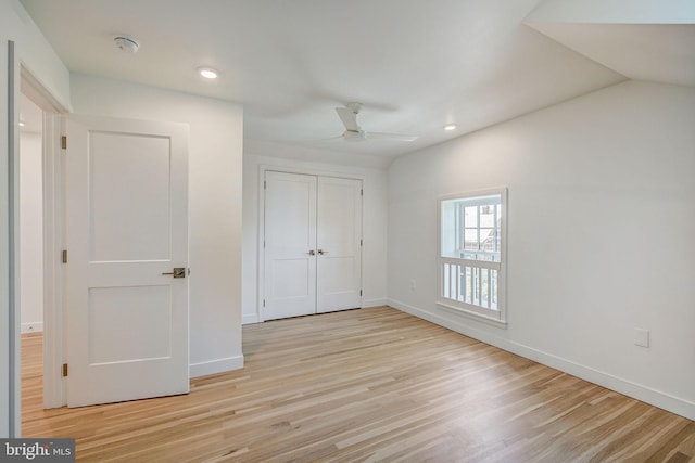 unfurnished bedroom featuring lofted ceiling, a closet, ceiling fan, and light wood-type flooring