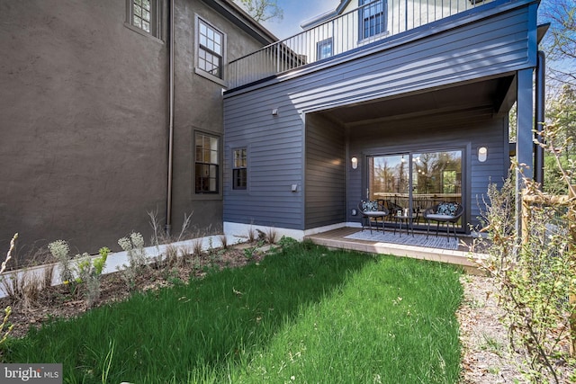 exterior space with a balcony and a lawn