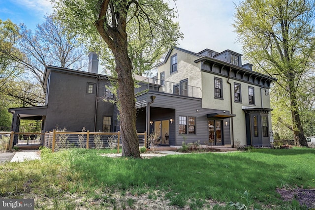 back of property with a yard and a balcony