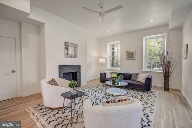 living room with light hardwood / wood-style flooring, a fireplace, and ceiling fan