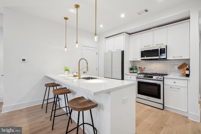 kitchen featuring sink, white cabinets, hanging light fixtures, stainless steel appliances, and light stone countertops