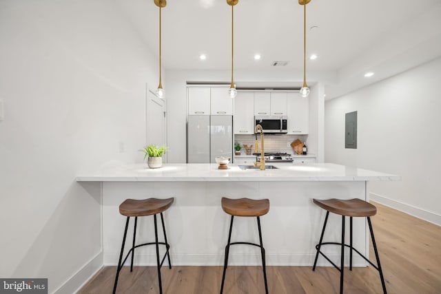 kitchen featuring pendant lighting, white fridge, white cabinets, and a kitchen bar