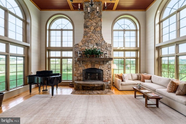 living room with an inviting chandelier, wooden ceiling, a high ceiling, and light wood-type flooring