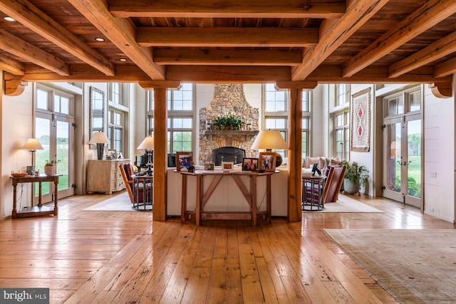 interior space with a healthy amount of sunlight, a stone fireplace, wood ceiling, and french doors