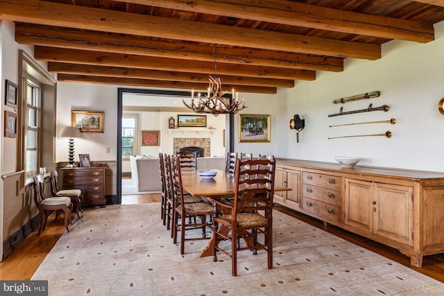 dining space featuring beamed ceiling, wooden ceiling, light wood-type flooring, and an inviting chandelier