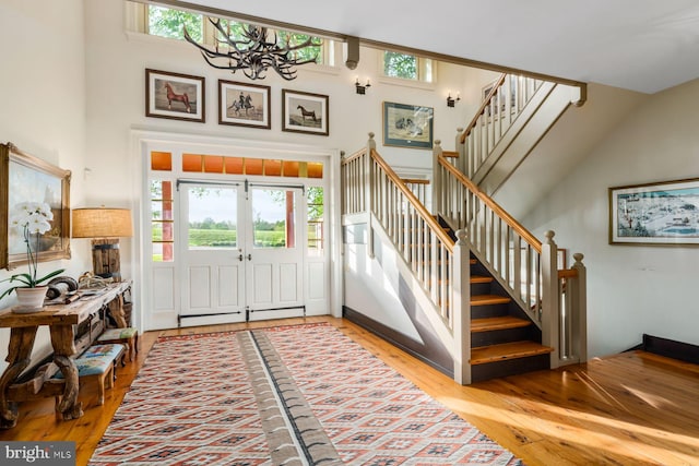 entrance foyer with lofted ceiling, hardwood / wood-style flooring, an inviting chandelier, and a baseboard heating unit