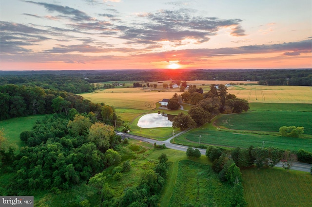 aerial view at dusk featuring a rural view and a water view