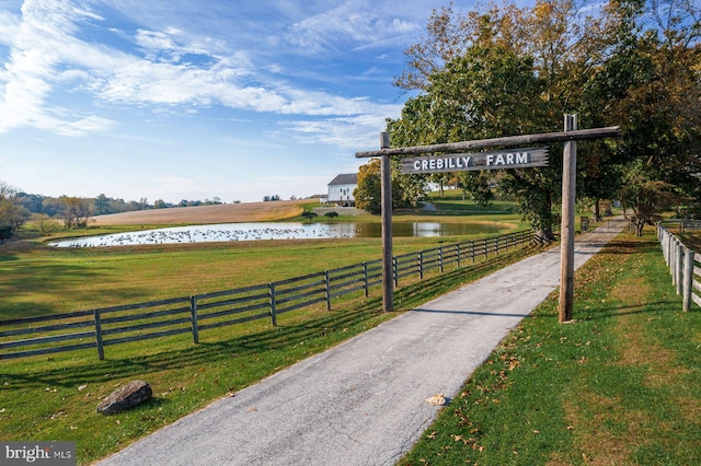 view of property's community featuring a rural view, a lawn, and a water view