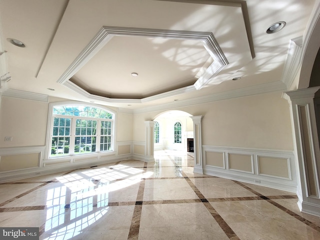 interior space featuring decorative columns, crown molding, and a tray ceiling