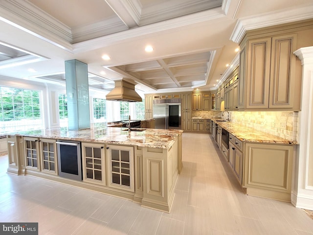 kitchen with light stone countertops, a healthy amount of sunlight, built in refrigerator, and a large island