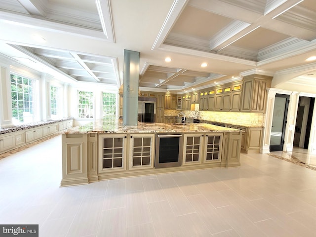 kitchen featuring coffered ceiling, wine cooler, light stone counters, backsplash, and a spacious island