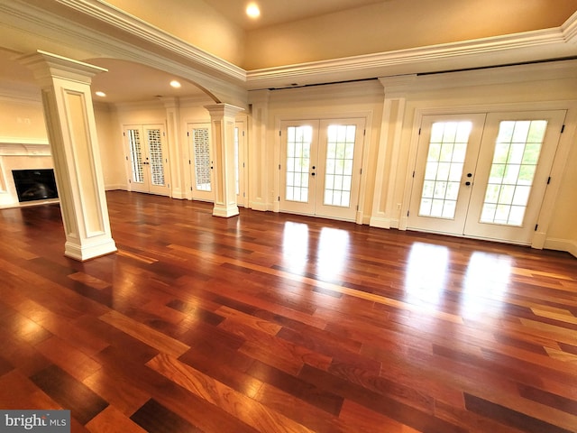 unfurnished living room featuring decorative columns, french doors, dark hardwood / wood-style floors, and ornamental molding