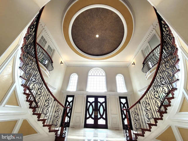 entryway with a high ceiling, french doors, and ornamental molding