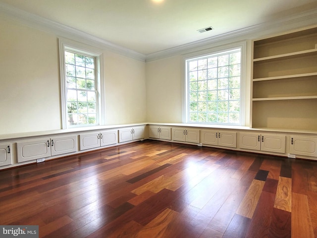 spare room with built in shelves, crown molding, and dark wood-type flooring