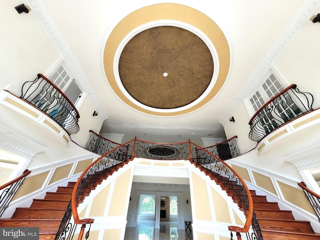 staircase with hardwood / wood-style floors, a towering ceiling, and french doors