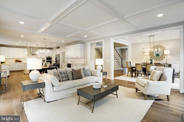 living room featuring a chandelier, coffered ceiling, and light hardwood / wood-style flooring