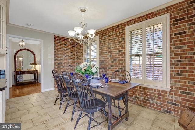 dining area with baseboards, a notable chandelier, and brick wall