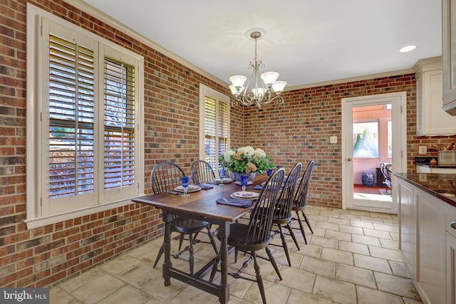 dining area with a chandelier and brick wall