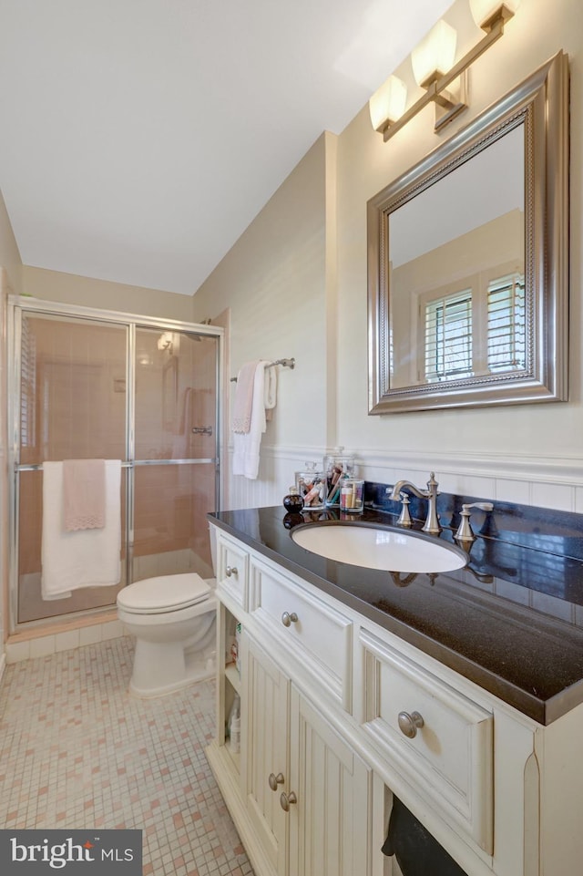 full bathroom with toilet, a wainscoted wall, tile patterned flooring, vanity, and a shower stall