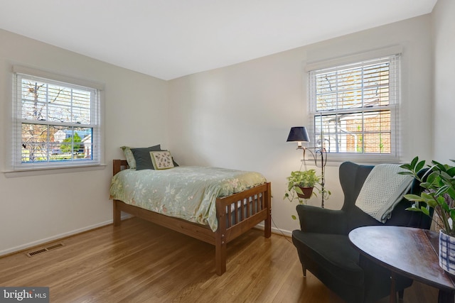 bedroom with light wood finished floors, baseboards, and visible vents