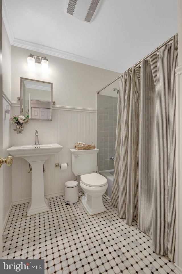 full bathroom featuring a wainscoted wall, crown molding, shower / bath combination with curtain, visible vents, and toilet