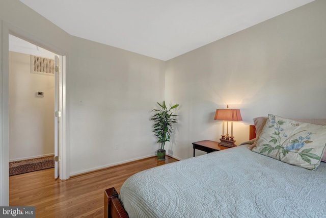 bedroom with wood finished floors, visible vents, and baseboards