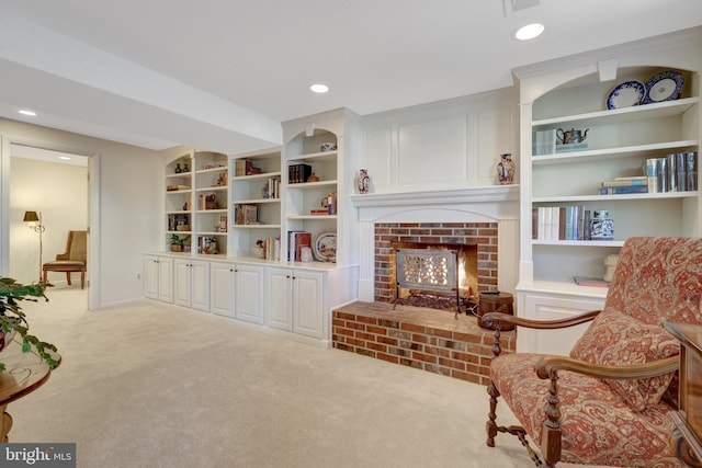 sitting room with carpet floors, built in shelves, a brick fireplace, and recessed lighting