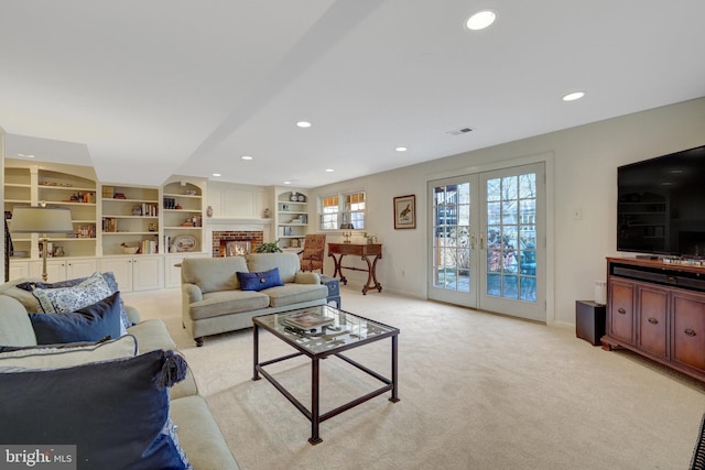 living area with light carpet, visible vents, baseboards, french doors, and a brick fireplace