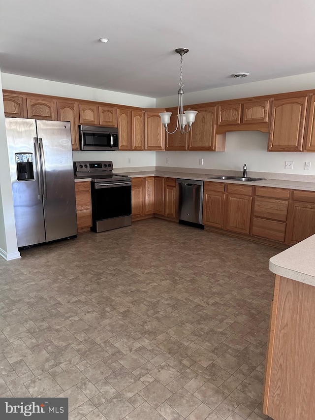 kitchen with appliances with stainless steel finishes, an inviting chandelier, pendant lighting, and sink