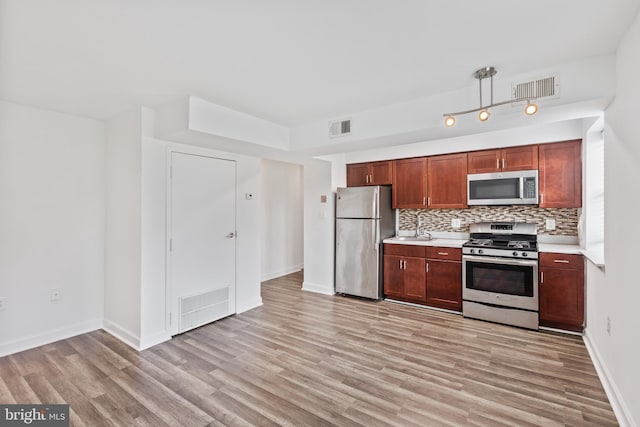 kitchen with light hardwood / wood-style floors, appliances with stainless steel finishes, and tasteful backsplash