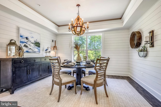 dining area with an inviting chandelier, a tray ceiling, hardwood / wood-style flooring, and ornamental molding