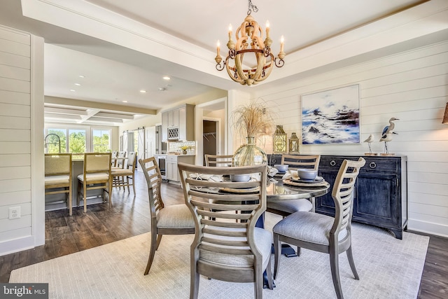 dining room featuring a notable chandelier, a tray ceiling, and dark wood-type flooring