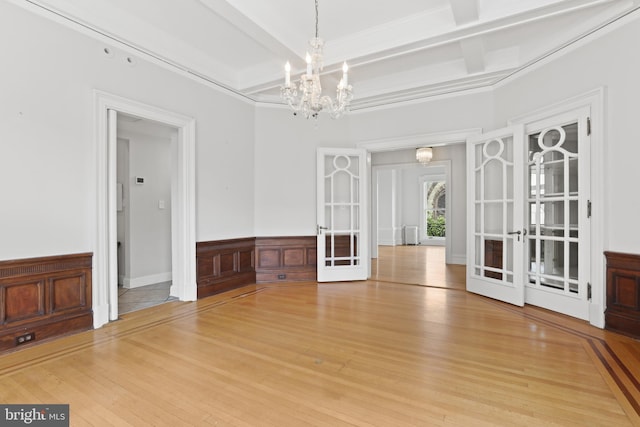 unfurnished room featuring beam ceiling, a notable chandelier, light wood-type flooring, and french doors