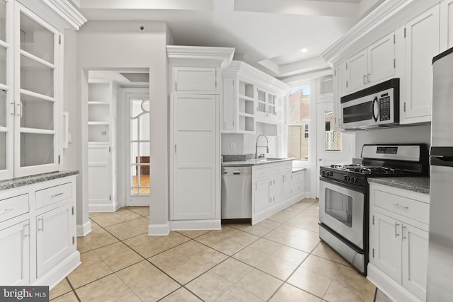 kitchen with appliances with stainless steel finishes, light tile floors, sink, white cabinetry, and a raised ceiling