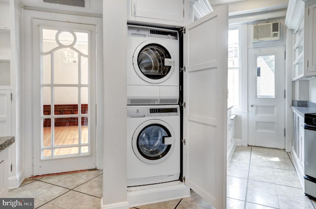 clothes washing area with a wall mounted air conditioner, stacked washer / dryer, and light tile floors