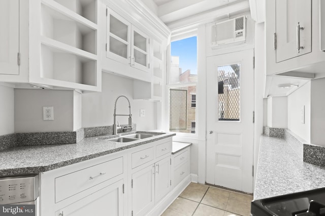 kitchen featuring light stone countertops, a wall unit AC, white cabinets, sink, and light tile floors