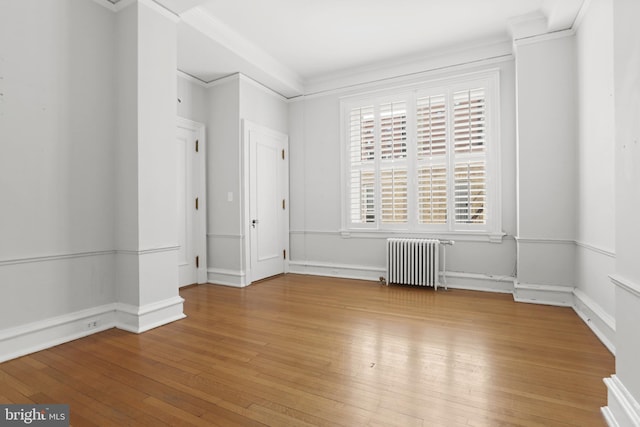 empty room with ornamental molding, light hardwood / wood-style flooring, and radiator