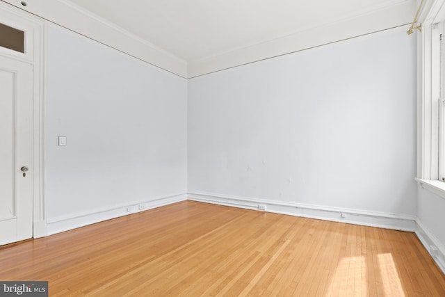 spare room featuring ornamental molding and light wood-type flooring