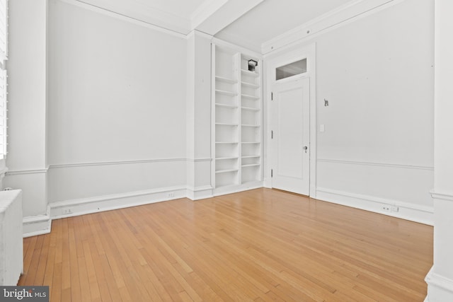 spare room with ornamental molding, built in features, radiator heating unit, and light wood-type flooring