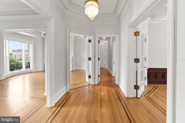 hall featuring ornamental molding, a notable chandelier, and light hardwood / wood-style flooring