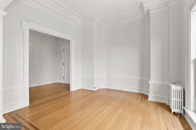 empty room with ornamental molding, light hardwood / wood-style floors, and radiator heating unit