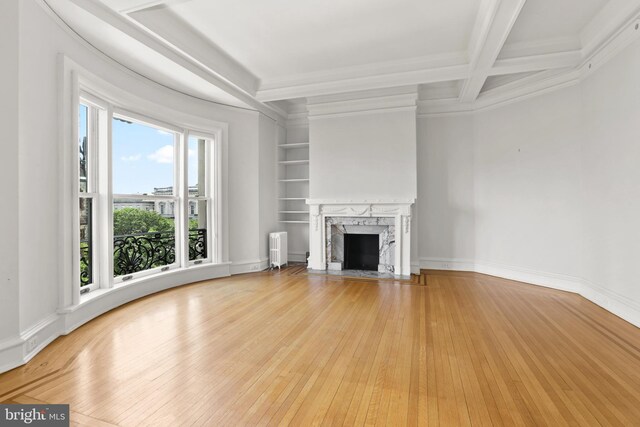 unfurnished living room featuring beam ceiling, light wood-type flooring, a wealth of natural light, and a premium fireplace