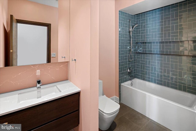 full bathroom featuring tile floors, vanity with extensive cabinet space, tiled shower / bath combo, and toilet