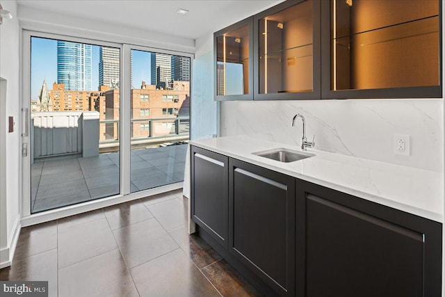 kitchen with backsplash, dark tile floors, sink, and light stone counters