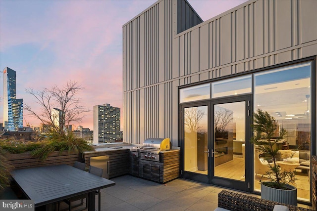 patio terrace at dusk featuring a grill and an outdoor kitchen