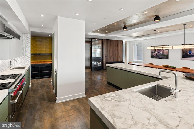 kitchen featuring sink, tasteful backsplash, pendant lighting, and a tray ceiling