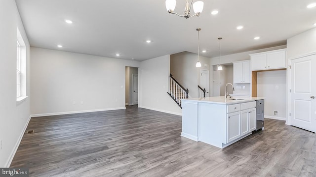 kitchen featuring a center island with sink, pendant lighting, wood-type flooring, and white cabinetry