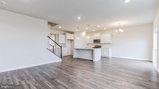 unfurnished living room with sink, wood-type flooring, and an inviting chandelier